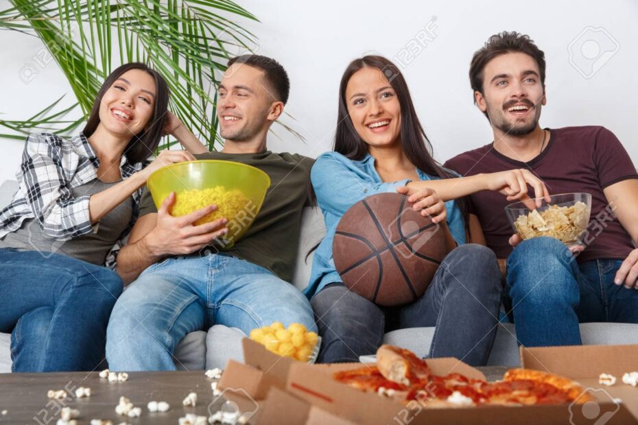 high school friends watching March Madness basketball game together cheering in living room